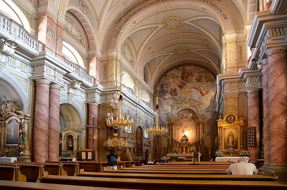 nterior of Sibiu’s Roman Catholic Church: pink ‘marble’ columns, chandeliers, frescoed apse.